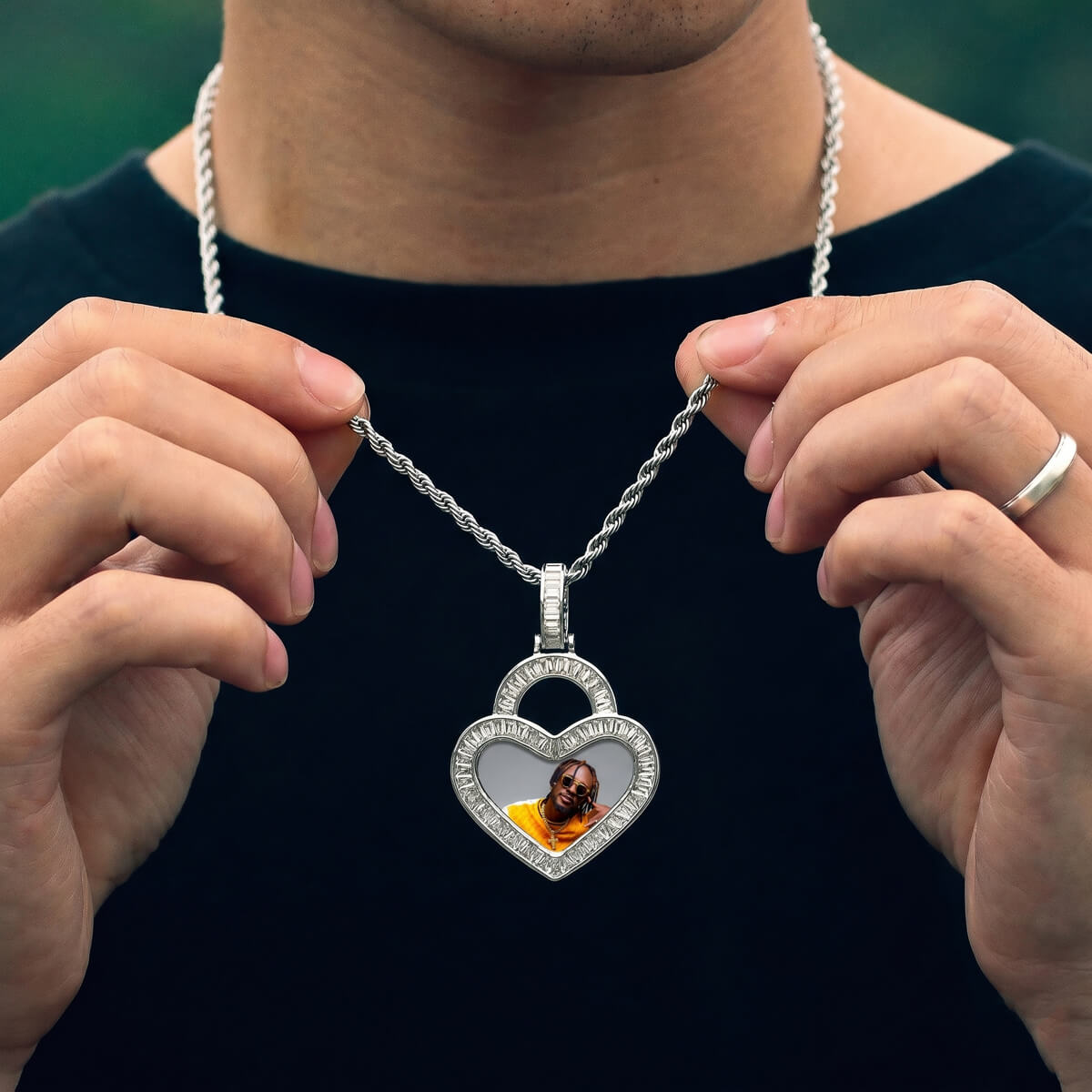 Person wearing iced out heart picture necklace
