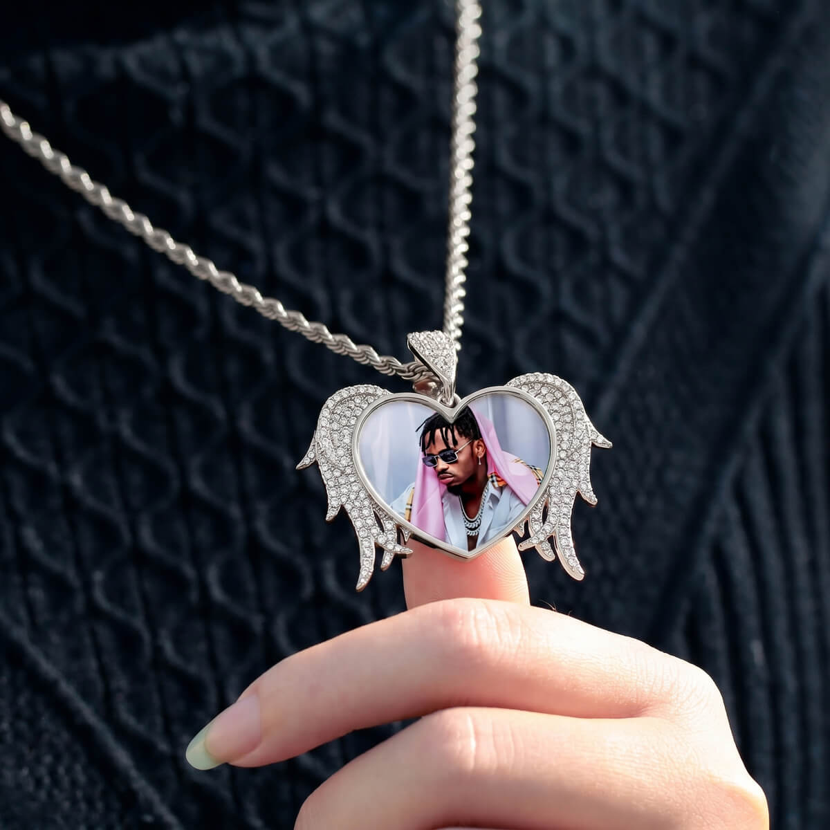 Person holding heart angel wings pendant necklace