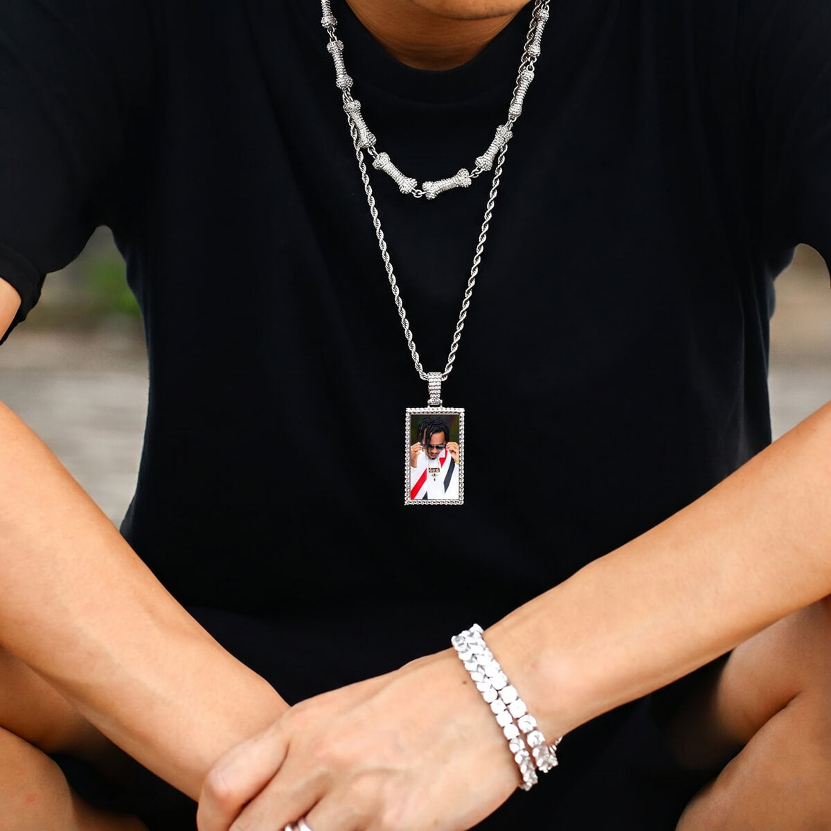 Person wearing rectangle iced out picture pendant necklace