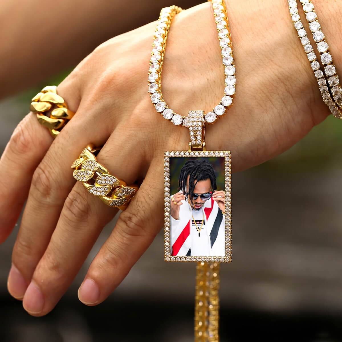 Hand wearing a picture necklace with a pendant featuring a photo of a person.