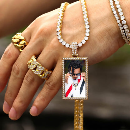Hand wearing a picture necklace with a pendant featuring a photo of a person.
