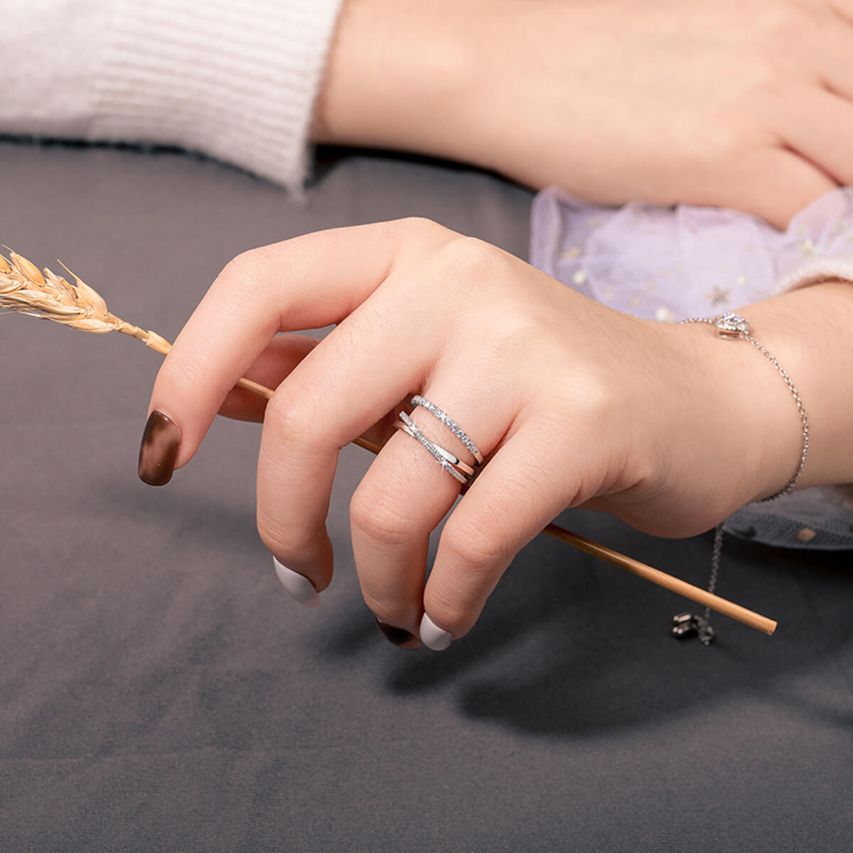 Close-up of Twisted Crossover Wedding Band Ring on finger featuring a modern intertwined design and brilliant white stones.